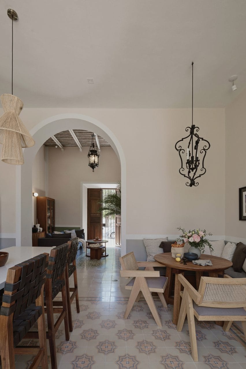 Interior de uma cozinha com piso de mosaico, área de café da manhã de canto e arco que leva à sala de estar